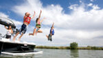 Kids jumping into water off boat
