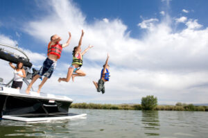 Kids jumping into water off boat